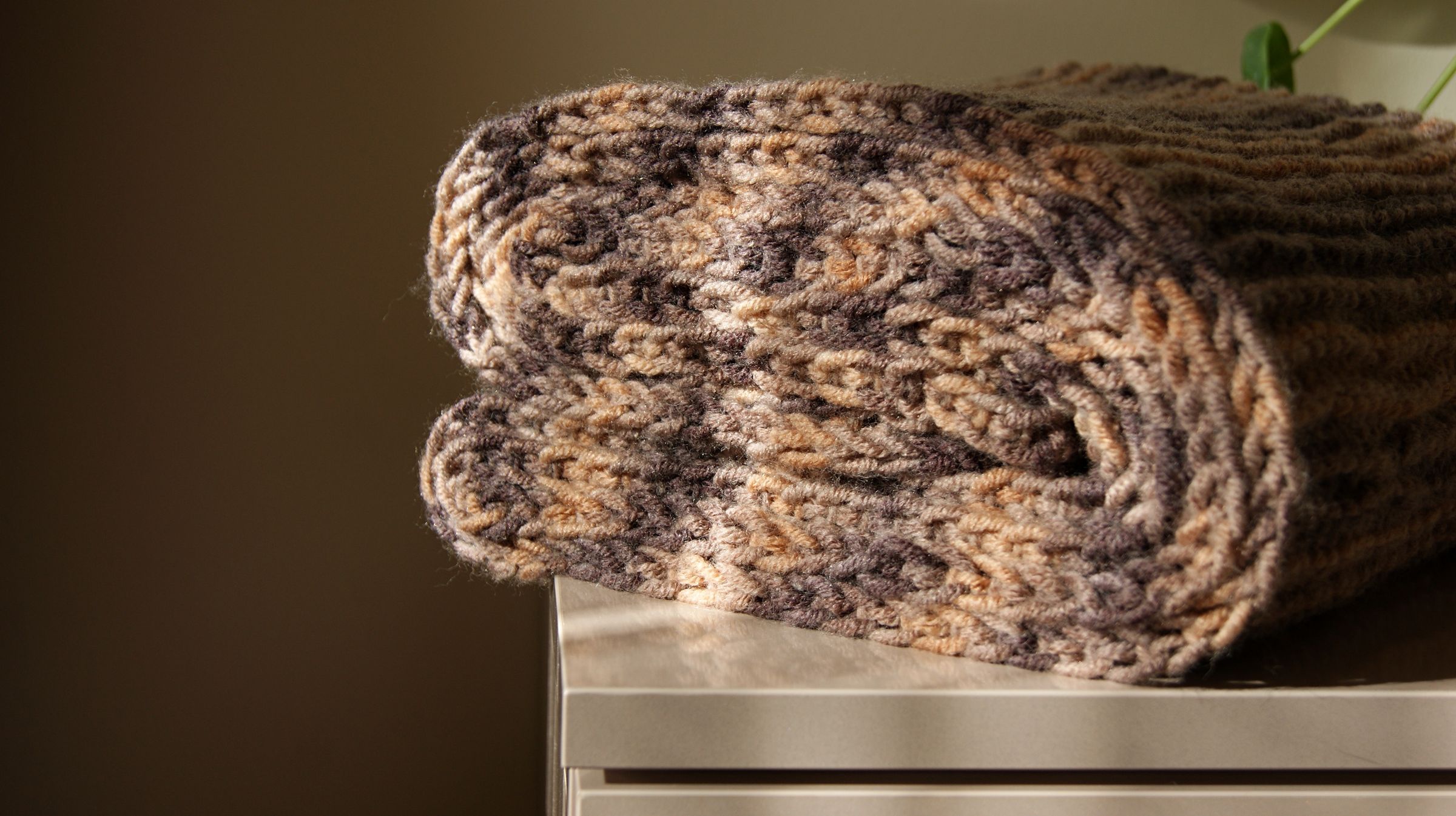 A folded knit blanket in warm light.